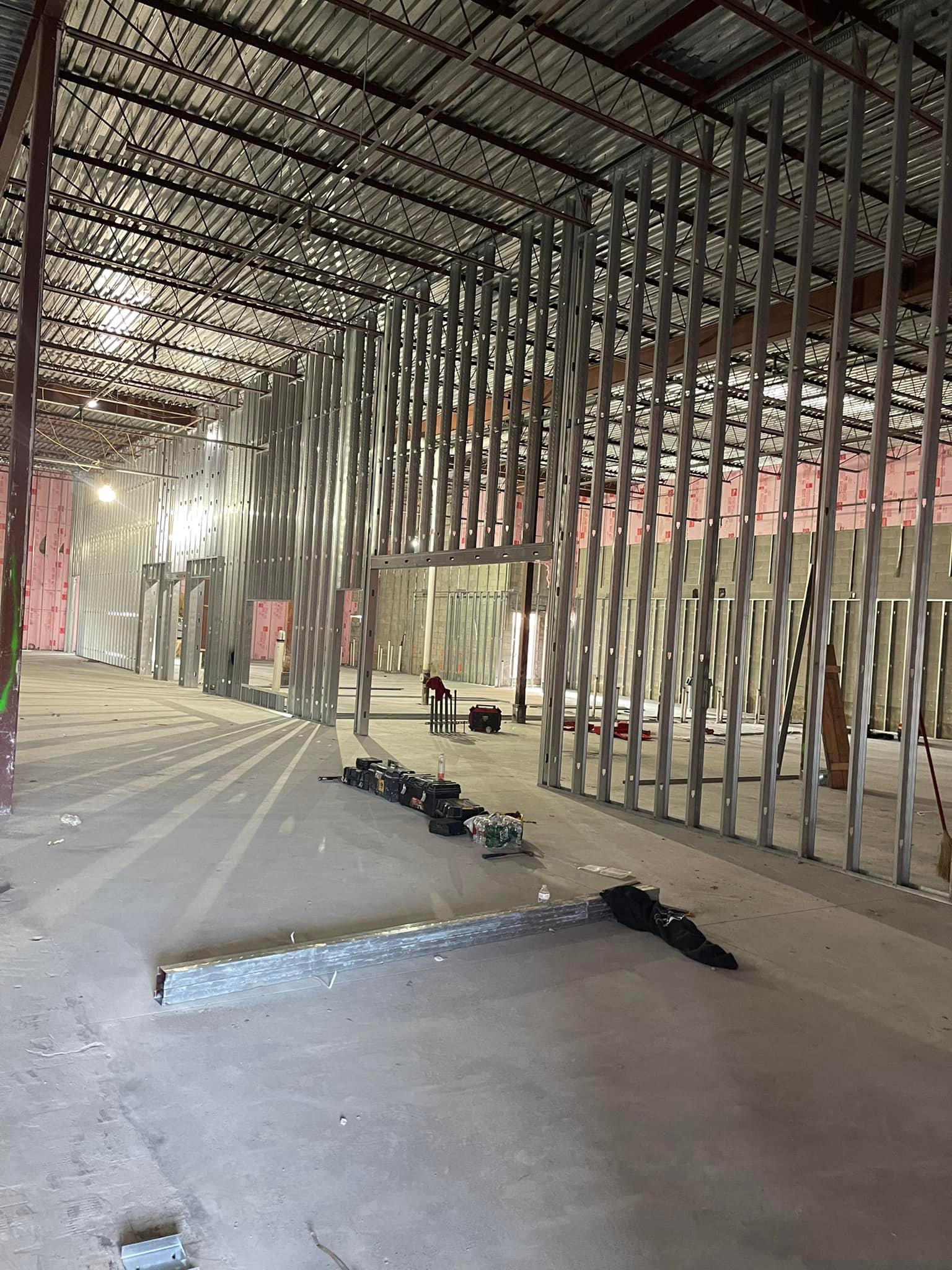 Office construction in progress with steel stud framing, open floor plan layout, and exposed ceiling structure